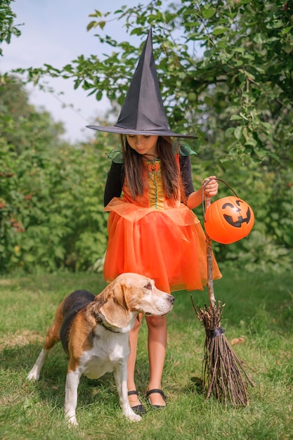 Chica va con perro a la búsqueda de dulces de Halloween