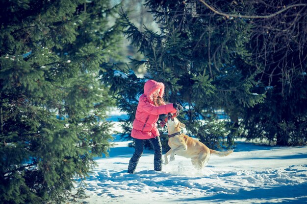 Chica con un perro cachorro Labrador jugando en invierno diversión al aire libre