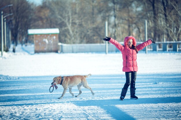 Chica con un perro cachorro Labrador jugando en invierno diversión al aire libre