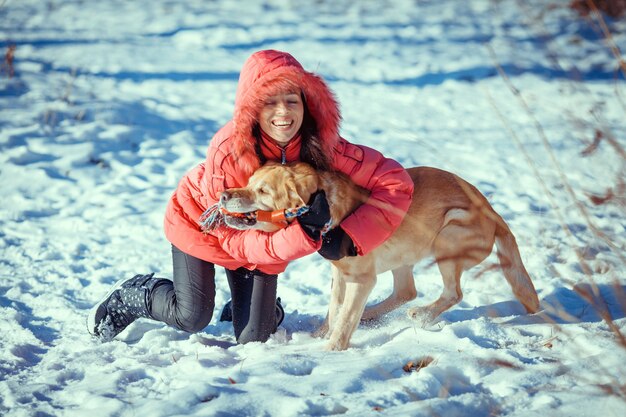 Chica con un perro cachorro Labrador jugando en invierno diversión al aire libre