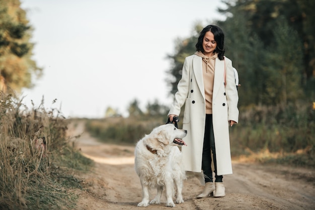 Chica con perro golden retriever blanco en el sendero del bosque