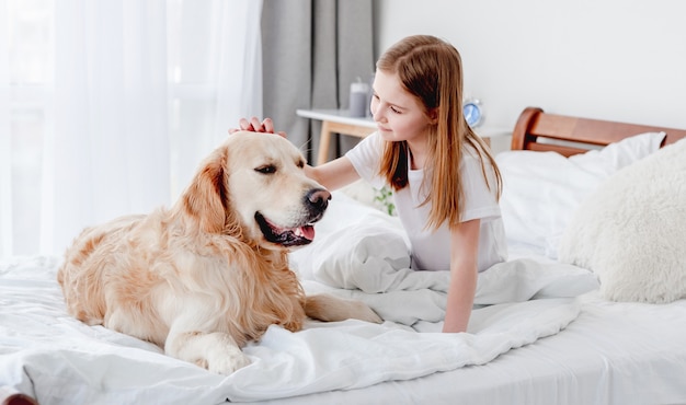 Chica con perro golden retriever en la cama