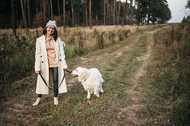 Chica con perro golden retriever caminando por el sendero del bosque