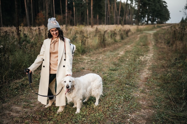 Chica con perro golden retriever caminando por el sendero del bosque