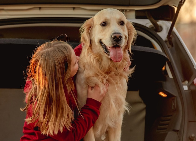 Chica con perro golden retriever en coche