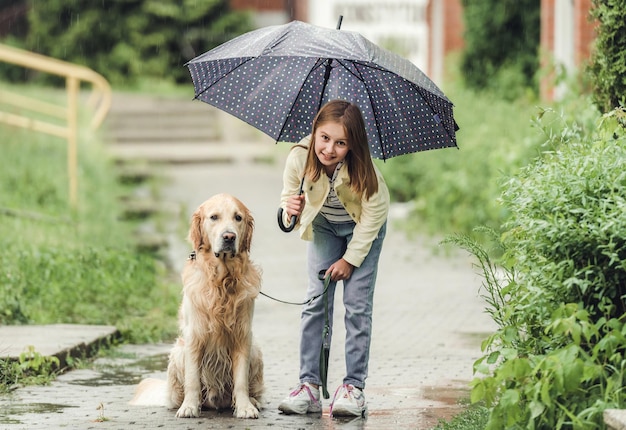 Chica con perro golden retriever en día lluvioso