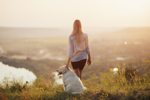 chica con perro golden retriever de pie en la colina