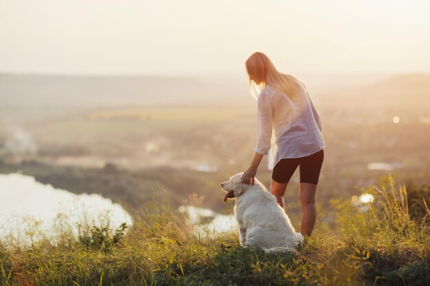 chica con el perro parado en una colina