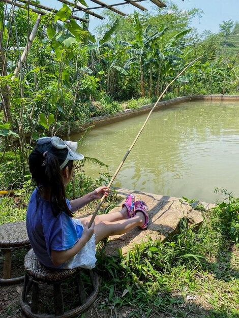 Foto una chica está pescando pacientemente en una piscina