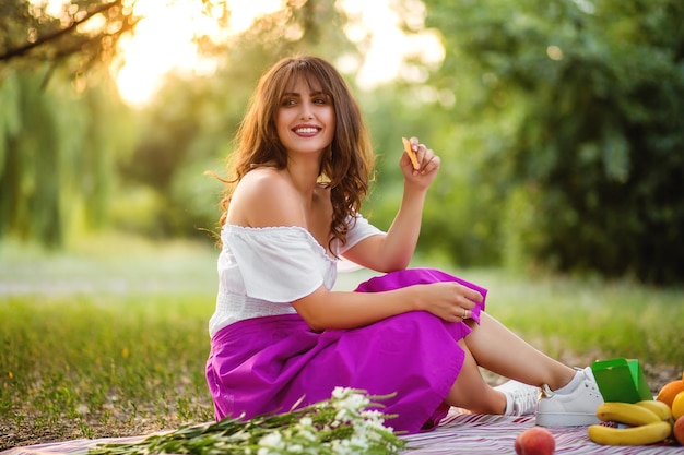 Foto chica en un picnic comiendo bocadillos y riendo