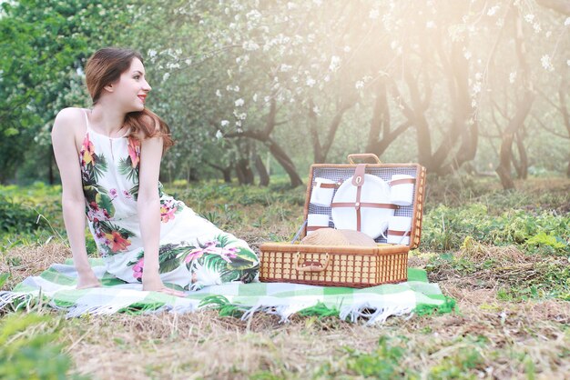 Chica de picnic en el huerto de manzanas con una cesta de productos