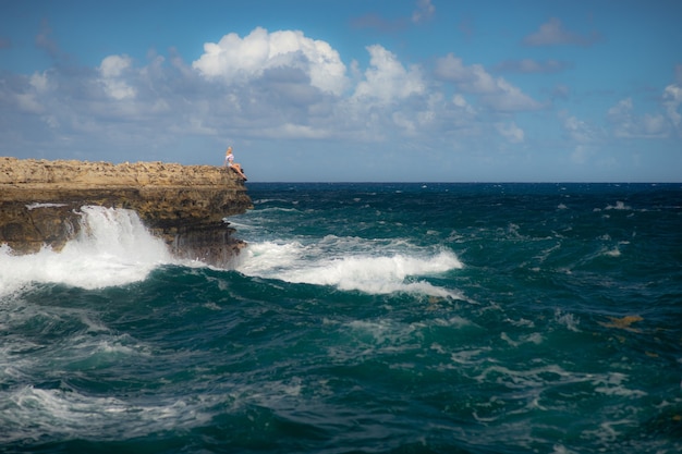 Chica de pie en el borde de la bahía del Puente del Diablo - mar tropical del Caribe - Antigua y Barbuda. Concepto de libertad un poder