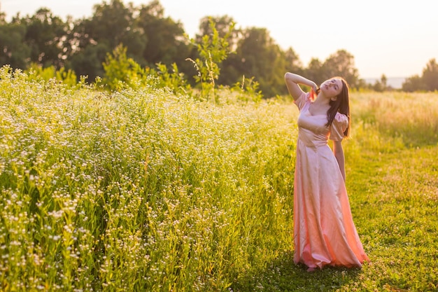 Chica de pie en el campo con un vestido rosa