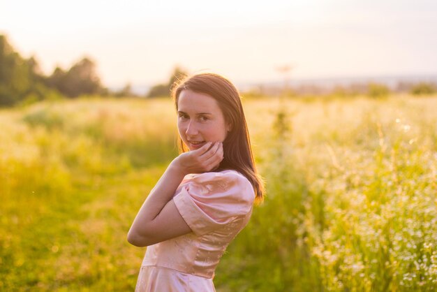 Chica de pie en el campo con un vestido rosa