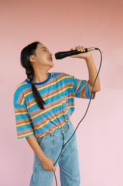 La chica de pie y cantando música sobre fondo rosa.