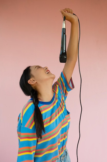 La chica de pie y cantando música sobre fondo rosa.