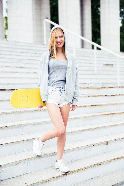 Chica de pie en las escaleras con patineta