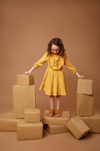 Chica de pie sobre una caja con un regalo rodeado de muchas cajas