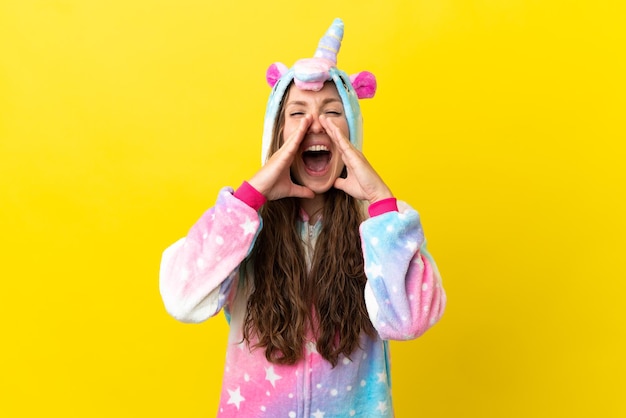 Chica con pijama de unicornio sobre fondo aislado gritando y anunciando algo