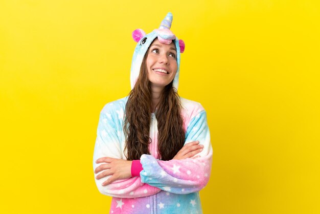 Chica con pijama de unicornio sobre un fondo aislado mirando hacia arriba mientras sonríe