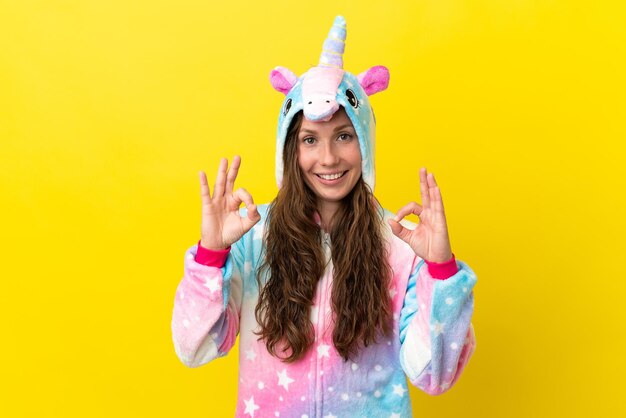 Chica con pijama de unicornio sobre fondo aislado mostrando un signo de ok con los dedos