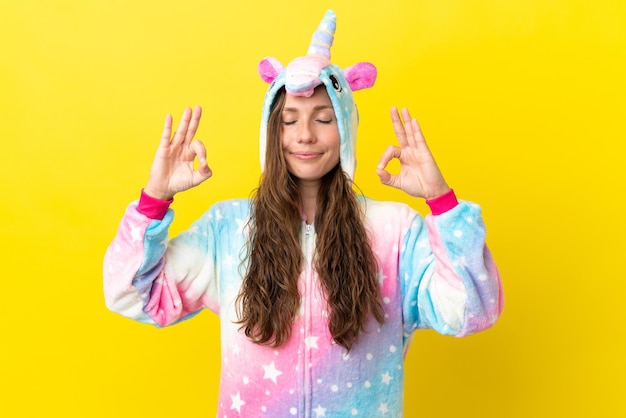 Chica con pijama de unicornio sobre fondo aislado en pose zen