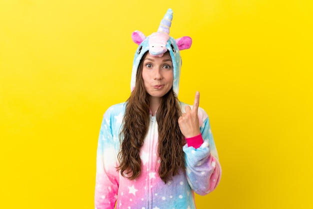 Chica con pijama de unicornio sobre fondo aislado señalando con el dedo índice una gran idea