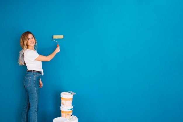 Chica pintando pared con rollo