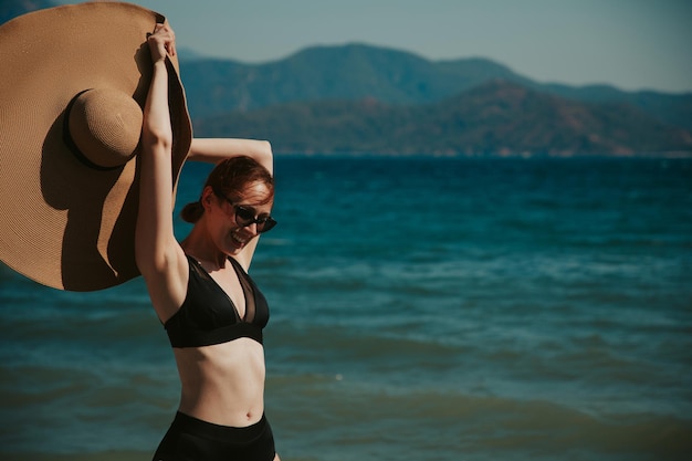 Chica en la playa, gran sombrero en el mar.