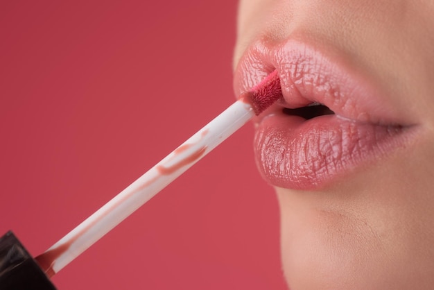 Chica pone lápiz labial en los labios con un pincel primer plano de labios de mujer con lápiz labial aplicando lápiz labial en un
