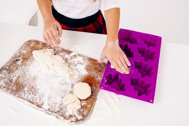 Chica pone masa cruda en forma de pasteles