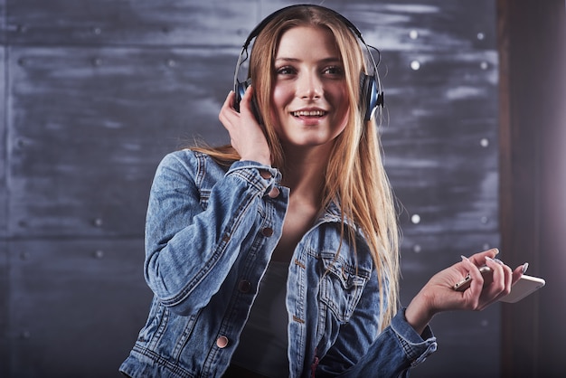 Chica posa en el estudio escucha música en auriculares