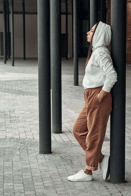 Chica posando en la calle cerca de columnas negras. Paseos y entretenimiento en la ciudad.