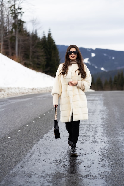 Chica posando en el camino en el bosque de invierno.