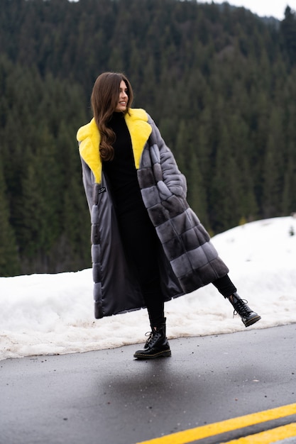 Chica posando en carretera en las montañas de invierno