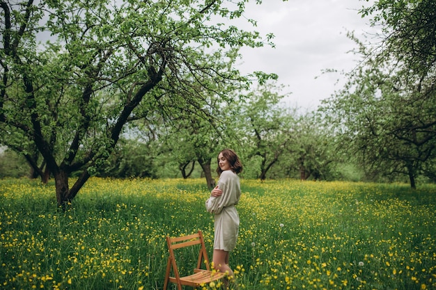 Chica posando en el jardín botánico Alrededor de la exuberante hierba y flores amarillas