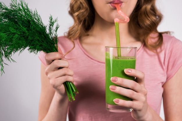 Chica posando con jugo verde y vegetación aislada