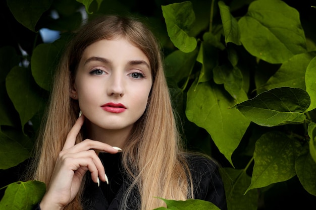 Chica posando en la pared con hojas verdes.