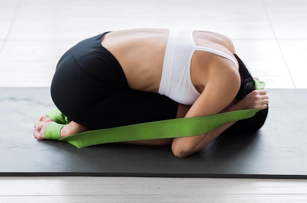 Una chica posando en posición fetal tirando de una cinta de gimnasia Foto horizontal
