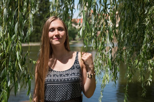 Chica posando con vides de sauce en jardín verde