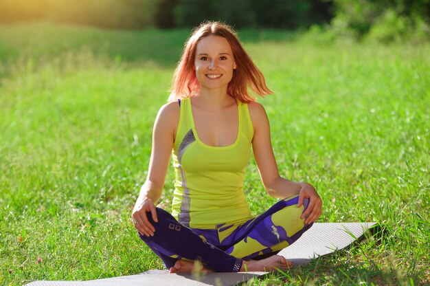 Chica posando yoga afuera en el bosque por la mañana