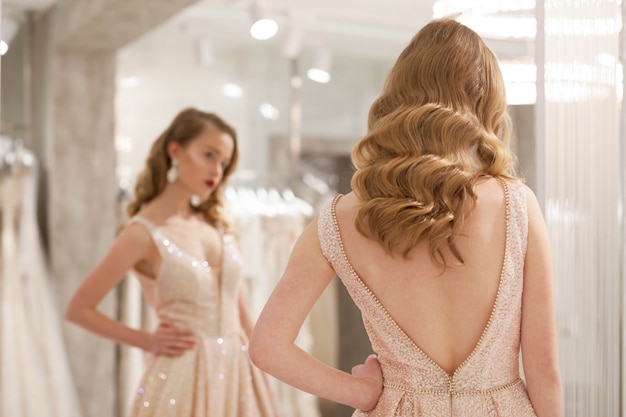 Chica posar en la tienda de vestidos de novia