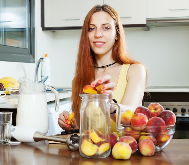 Foto chica positiva cocinando bebidas de duraznos