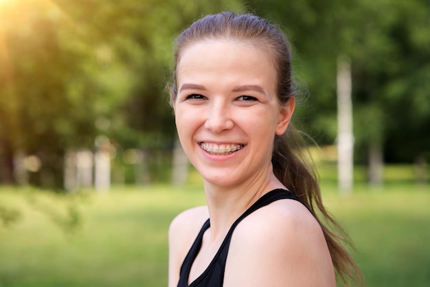 Chica positiva feliz con frenos en los dientes joven mujer hermosa al aire libre en el parque soleado de verano sonriendo