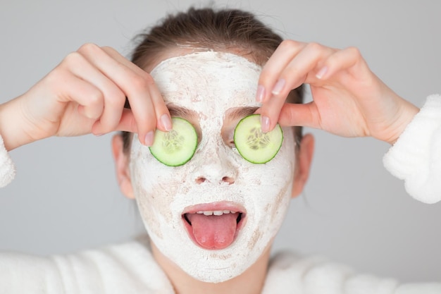 Chica positiva sosteniendo rodajas de pepino hasta los ojos Foto o