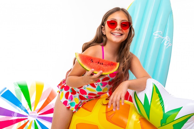 Chica positiva en traje de baño con una amplia sonrisa en su rostro, vacaciones de verano, fruta fresca