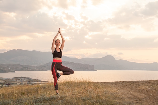 Chica practica yoga en las montañas en el océano.