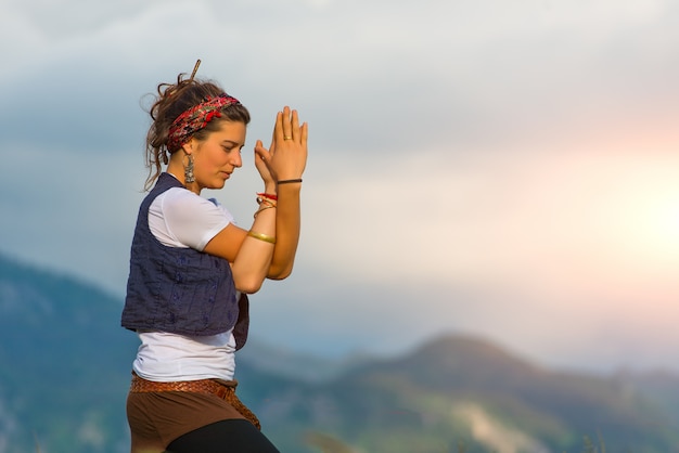 Chica practicando yoga en la naturaleza en las montañas