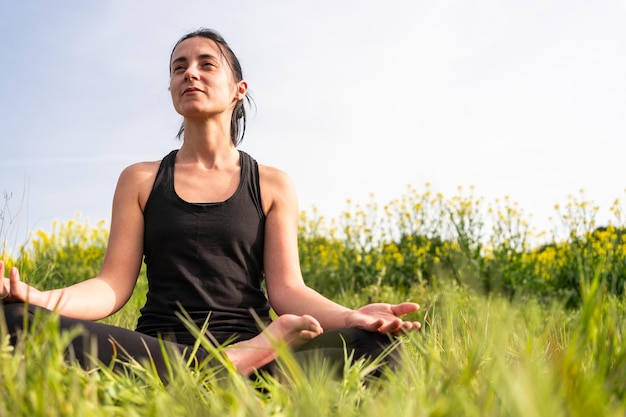 Chica practicando yoga en la naturaleza con ropa ajustada en verano