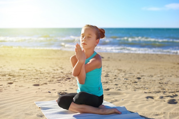 Chica practicando yoga en la playa Imagen entonada